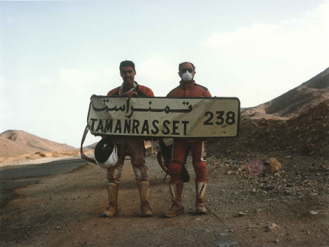 Luca e un suo amico mostrano un cartello con scritto Direzione Tamanrasset 238
